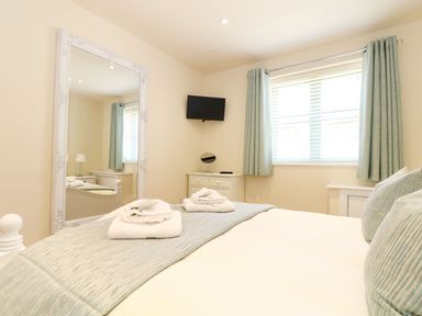 A bedroom with a bed and mirror at Elm Cottage in Truro