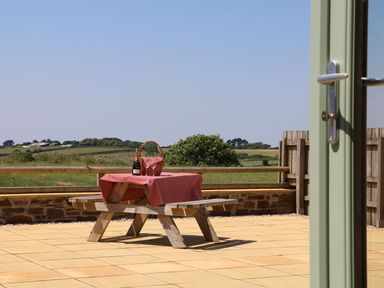 A table with a basket and wine in an outdoor area at Elm Cottage in Truro