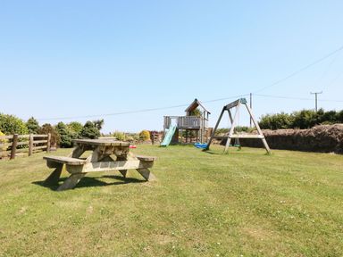 A garden with a picnic table and play equipment at Elm Cottage in Truro