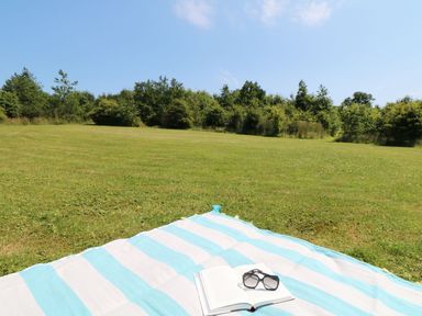 A blanket with a book and sunglasses in an outdoor area at Elm Cottage in Truro