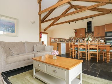 A living room with a sofa and dining area at Ash Cottage in Truro