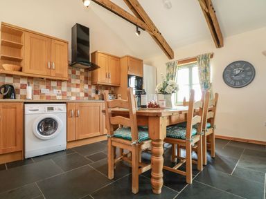A kitchen with wooden cabinets and a dining table at Ash Cottage in Truro