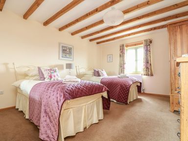 A bedroom with two beds and a wardrobe at Ash Cottage in Truro