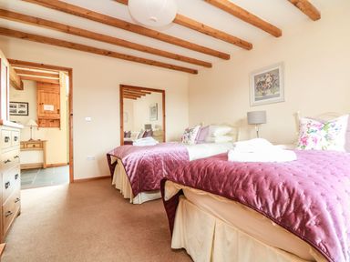 A bedroom with two beds and a mirror at Ash Cottage in Truro