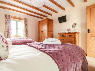 A bedroom with two beds and wooden furniture at Ash Cottage in Truro