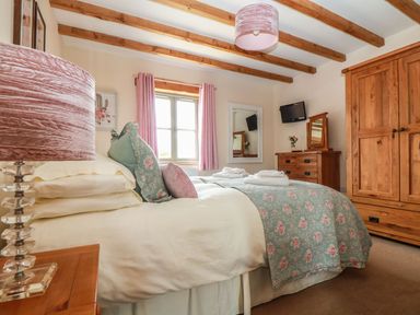 A bedroom with a bed and wardrobe at Ash Cottage in Truro