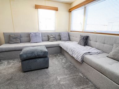 A living room with a sectional sofa and ottoman at Beach Fields 45 in Kinmel Bay