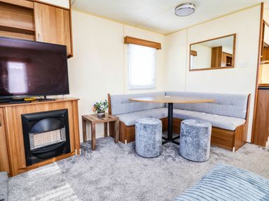 A living room with a television and bench seating at Beach Fields 45 in Kinmel Bay