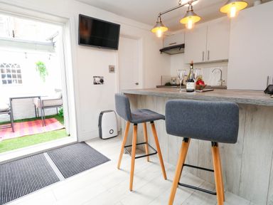 A kitchen with bar stools and a television at Flat 1, 2 Wooperton Street Weymouth