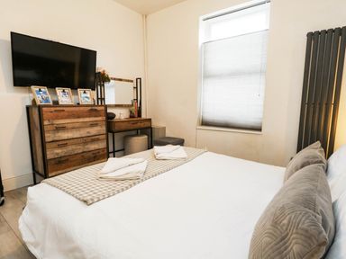A bedroom with a bed, dresser, and television at Flat 1, 2 Wooperton Street Weymouth