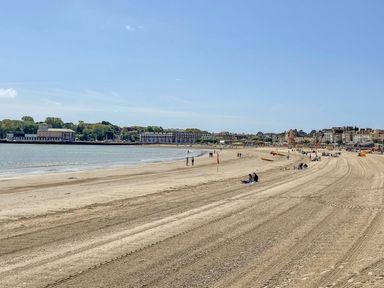 A beach with people and buildings at Flat 1, 2 Wooperton Street in Weymouth