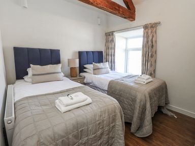A bedroom with two beds and a window at Hen Blas in Pwllheli