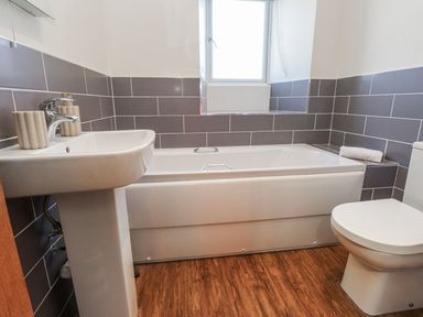A bathroom with a bath tub and sink at Hen Blas in Pwllheli