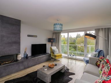 A living room with a television and sofa at 10 Rayrigg Rise Bowness-On-Windermere