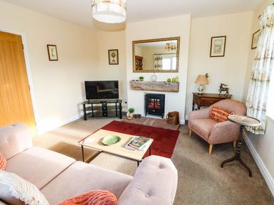 A living room with a sofa, armchair, and television at The Bungalow in Penrith