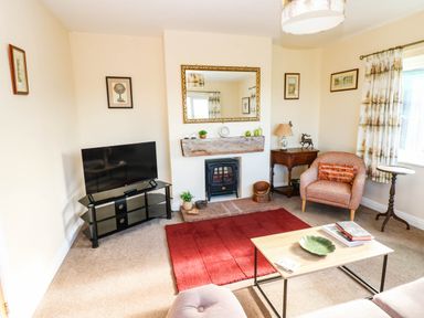 A living room with a television, fireplace and seating at The Bungalow in Penrith