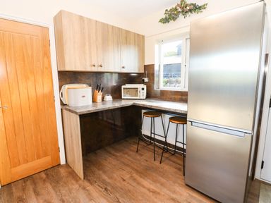A kitchen with countertop appliances and bar stools at The Bungalow in Penrith