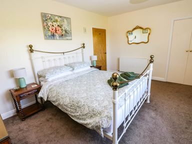 A bedroom with a bed, nightstand, and mirror at The Bungalow in Penrith
