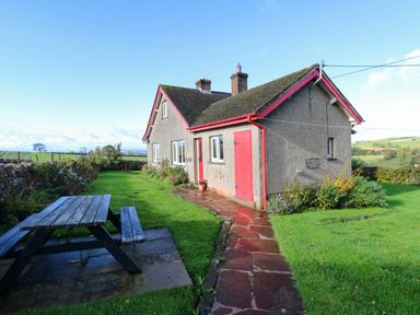 A house with a table and bench in the garden at The Bungalow in Penrith