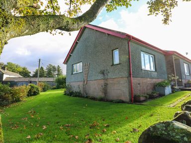 An exterior view of a house with green grass and trees at The Bungalow in Penrith