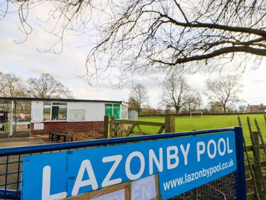 A pool facility with a sign and office building at Lazonby Pool in Penrith