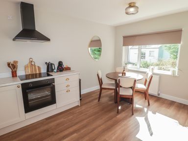 A kitchen with an oven and a table with chairs at Flat 2 in Tenby