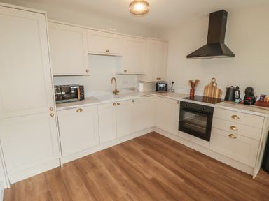 A kitchen with cabinets, oven, microwave, and utensils at Flat 2 in Tenby