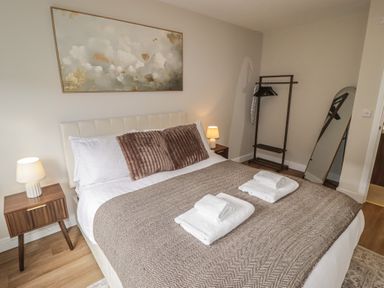 A bedroom with a bed, bedside table, and clothes rack at Flat 2 in Tenby