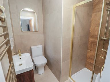 A bathroom with toilet, sink, shower and towel radiator at Flat 2 in Tenby