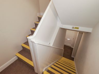 A staircase with yellow markings and a warning sign at Flat 2 in Tenby