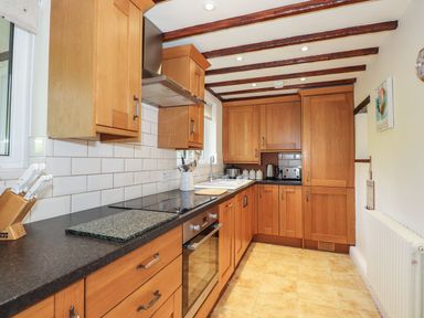 A kitchen with wooden cabinets and a stove at High Beck Cottage in Kendal
