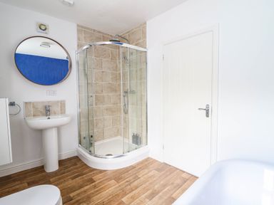 A bathroom with a shower, sink and a mirror at Flat 4 Greenfields Barmouth