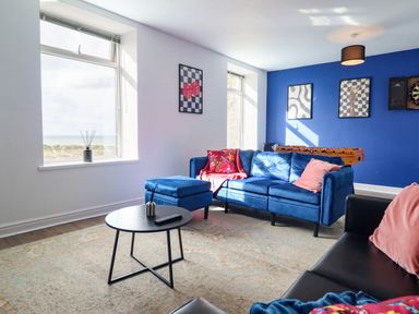 A living room with a blue sofa and coffee table at Flat 4 Greenfields Barmouth