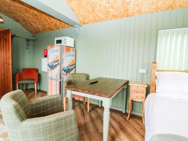 A sleeping area with a table and chairs at Calendonia Hut in West Mains near Haggerston