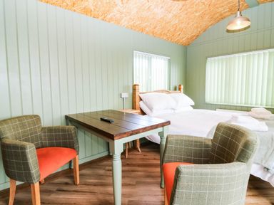 A bedroom with a bed and table at Calendonia Hut in West Mains near Haggerston