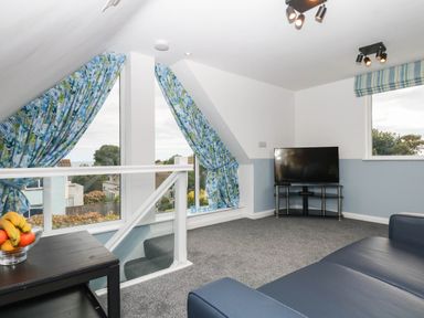 A living room with a television and sofa at Merlins Hideaway in Dawlish