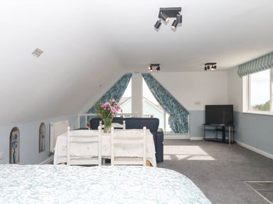 A loft with a bed and a seating area at Merlins Hideaway in Dawlish