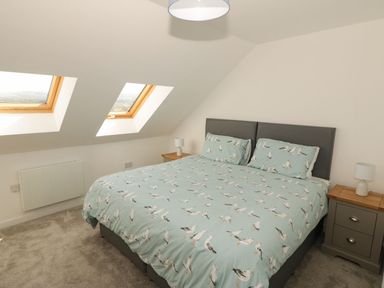A bedroom with a bed and windows at Cae Mawr in Caernarfon