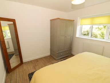 A bedroom featuring a bed, wardrobe, mirror, and window at Cae Mawr in Caernarfon