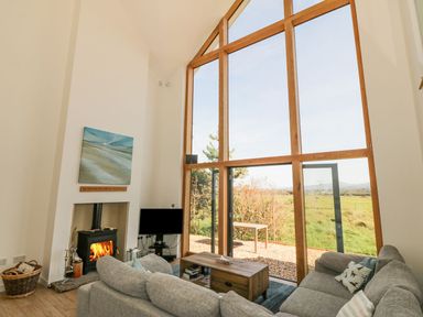A living room with a large window and a fireplace at Cae Mawr in Caernarfon
