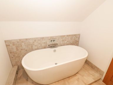 A bathroom with a bathtub and faucet at Cae Mawr in Caernarfon
