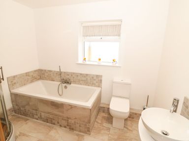 A bathroom with a bath tub, toilet, and sink at Cae Mawr in Caernarfon