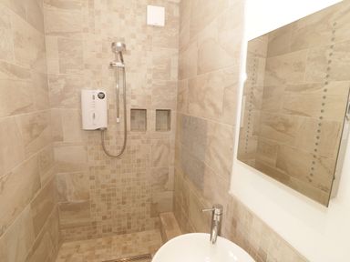 A bathroom with a shower and water heater at Cae Mawr in Caernarfon