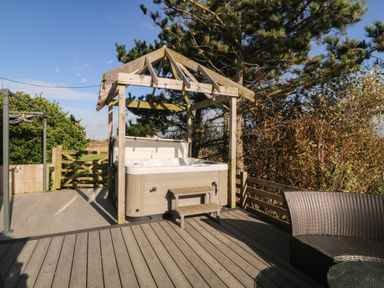 An outdoor deck with a hot tub at Cae Mawr in Dinas Dinlle
