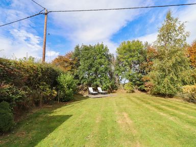 A garden with trees and deck chairs at The Gables in Alnwick