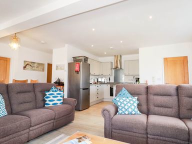 A living room with a sofa and kitchen in Apartment 3 Newquay
