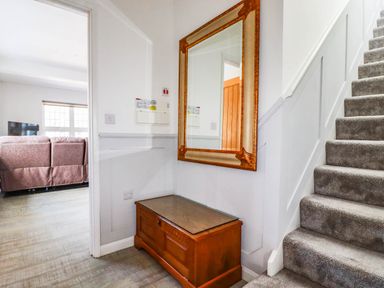 A hallway with a staircase and a wooden bench at Apartment 3 in Newquay
