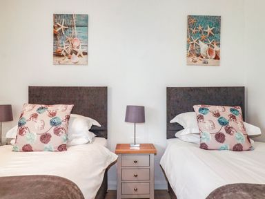 A bedroom with two beds and artwork on the wall at Apartment 3 in Newquay