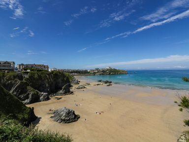 A beach with sand and rocks near a town at Apartment 3 Newquay