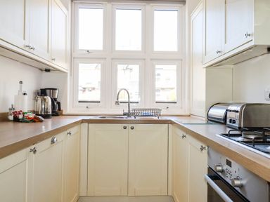 A kitchen with cabinets, sink, stove, and kettle at Apartment 1 in Newquay